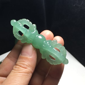 May include: A green jade carving of a Tibetan Buddhist ritual object, known as a Dorje, a double thunderbolt symbolising power and strength.