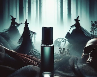 May include: A dark green glass bottle of perfume with a black cap sits on a wooden surface in front of a foggy forest scene. Three witches in black robes and pointed hats are visible in the background.