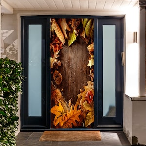 May include: A decorative door cover featuring a rustic wooden background framed by autumn leaves, acorns, and corn. The design includes a variety of fall foliage in shades of orange, yellow, and brown, creating a seasonal theme.