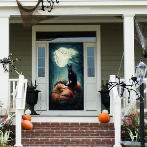 May include: A rectangular door cover featuring a printed Halloween scene with a black cat sitting on a pile of orange pumpkins under a full moon, bare tree branches, and a wooden fence against a dark, cloudy night sky background.