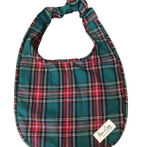 May include: A green, red, and white tartan bib with a rounded base and a gathered handle. The bib has a label that reads "Paper & Crane". The tartan pattern is a traditional design.