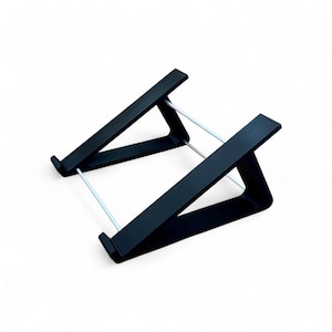 Può includere: Un supporto nero per laptop dal design minimalista. Il supporto è realizzato in legno nero e presenta una superficie inclinata sostenuta da un telaio triangolare e aste metalliche argentate. Il supporto è progettato per sollevare un laptop.