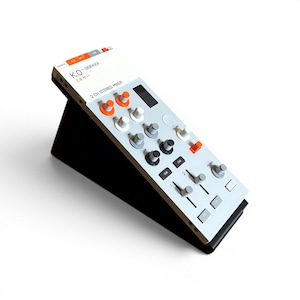 May include: A white K.O. SIDEKICK 2 CH STEREO MIXER with orange and grey knobs, sliders, and buttons. The device is mounted on a black angled stand. The control panel features labels including GAIN, HIGH, MID, LOW, CUE, and FX, with Japanese text.