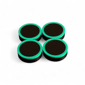 Peut inclure: Quatre objets ronds noirs avec un bord vert vif. Les objets sont disposés en carré sur un fond blanc. Les objets semblent petits, peut-être des dessous de verre ou des éléments décoratifs.