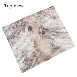 May include: Top view of a square cowhide pillow with a natural brindle pattern. The pillow features a mix of brown, white, and gray tones, creating a textured and organic appearance. The text "Top View" is in the top left corner.