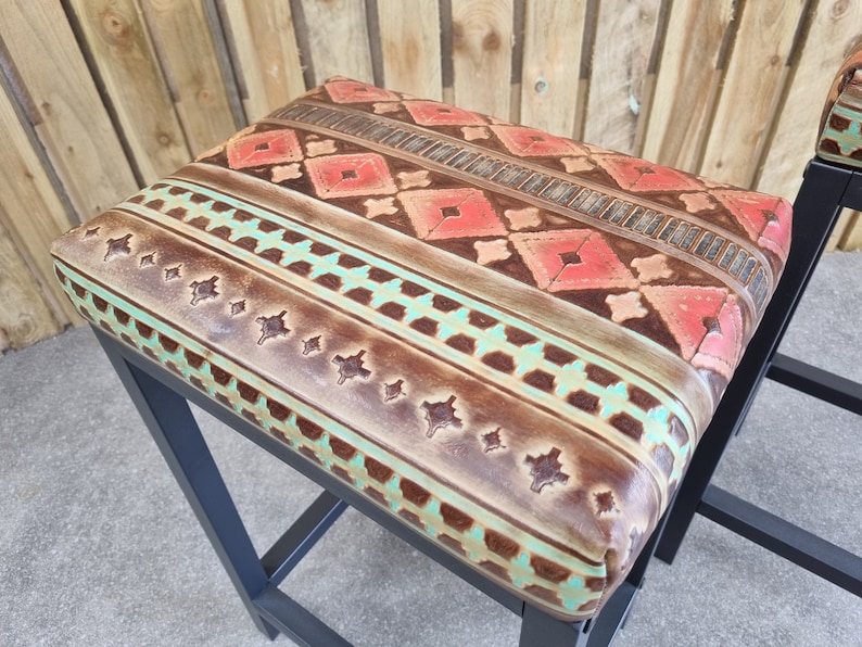 May include: A black metal bar stool with a brown leather seat featuring a turquoise and red geometric pattern.
