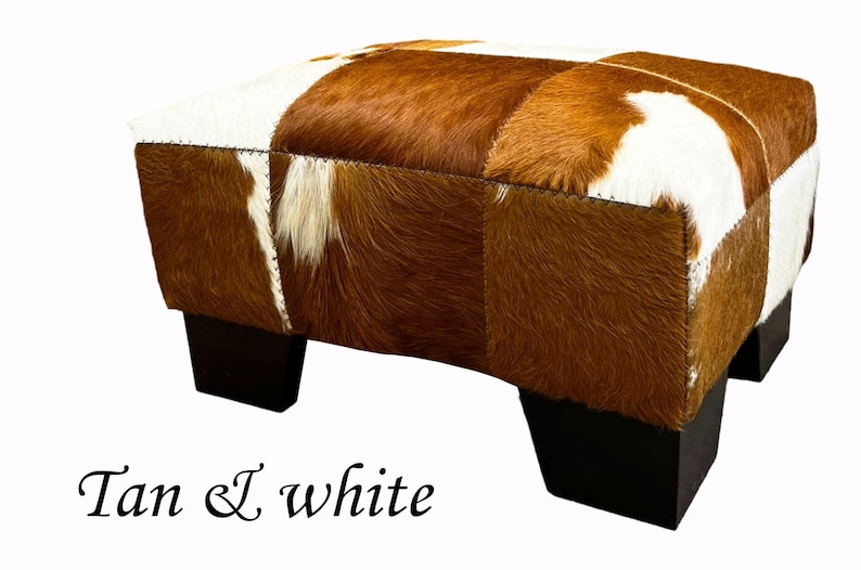 May include: Tan and white cowhide ottoman with four dark wood legs.