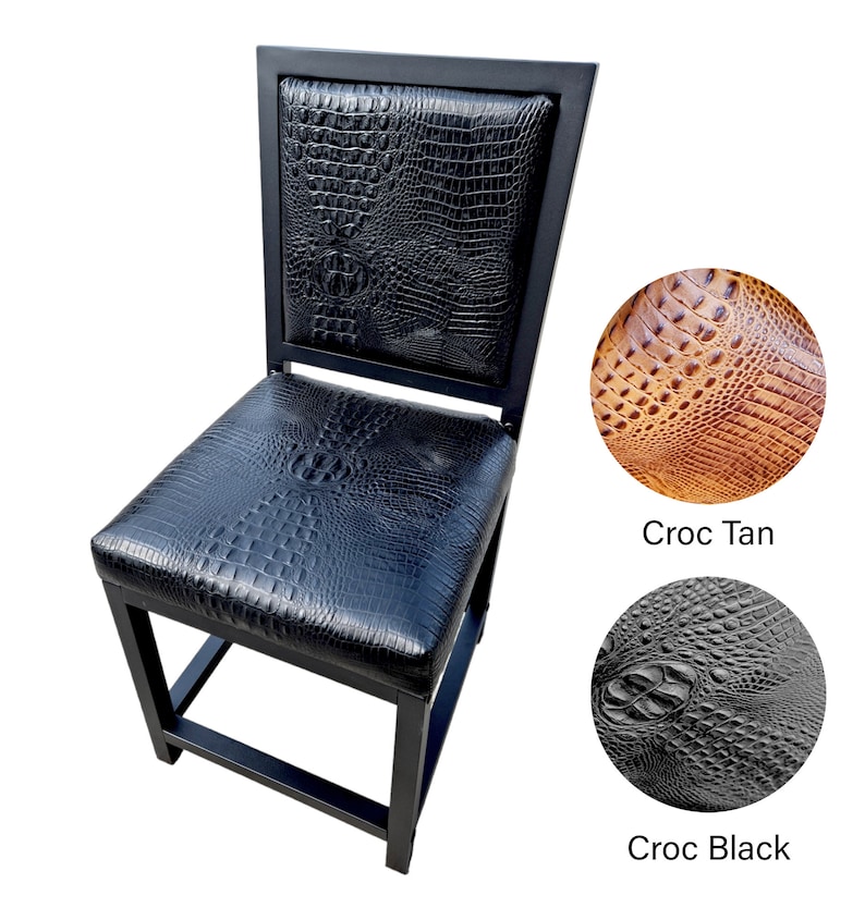 May include: Black metal chair with a black crocodile-embossed leather seat and back. The chair has a square back and a square seat. The chair is on a white background. Two close-up images of the leather are shown below the chair. The first image is of tan crocodile-embossed leather with the text "Croc Tan" below it. The second image is of black crocodile-embossed leather with the text "Croc Black" below it.