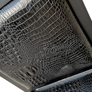 May include: Black leather chair with a crocodile pattern. The chair is made of a sturdy metal frame and has a comfortable seat.