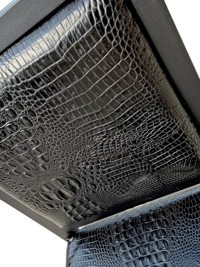May include: Black leather chair with a crocodile pattern. The chair is made of a sturdy metal frame and has a comfortable seat.