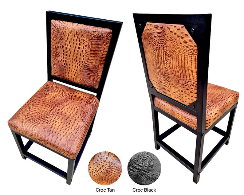 May include: Two black metal dining chairs with a crocodile embossed brown leather seat and back. The chairs have a square back and a simple design.