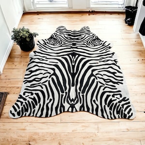 May include: Black and white zebra print rug with a long, narrow shape. The rug is made of a soft, plush material and has a natural, organic feel.