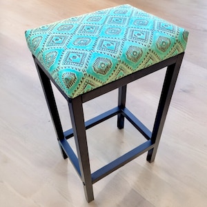 May include: A black metal bar stool with a turquoise and brown patterned cushion.