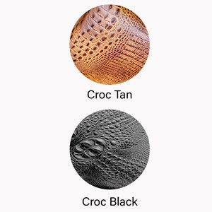 May include: Two circular samples of crocodile-textured leather. One is tan with a warm, brown hue, and the other is black. The text "Croc Tan" and "Croc Black" are below each sample, respectively. The samples are on a white background.