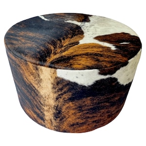 May include: Round brown, black, and white cowhide ottoman with a tufted top.