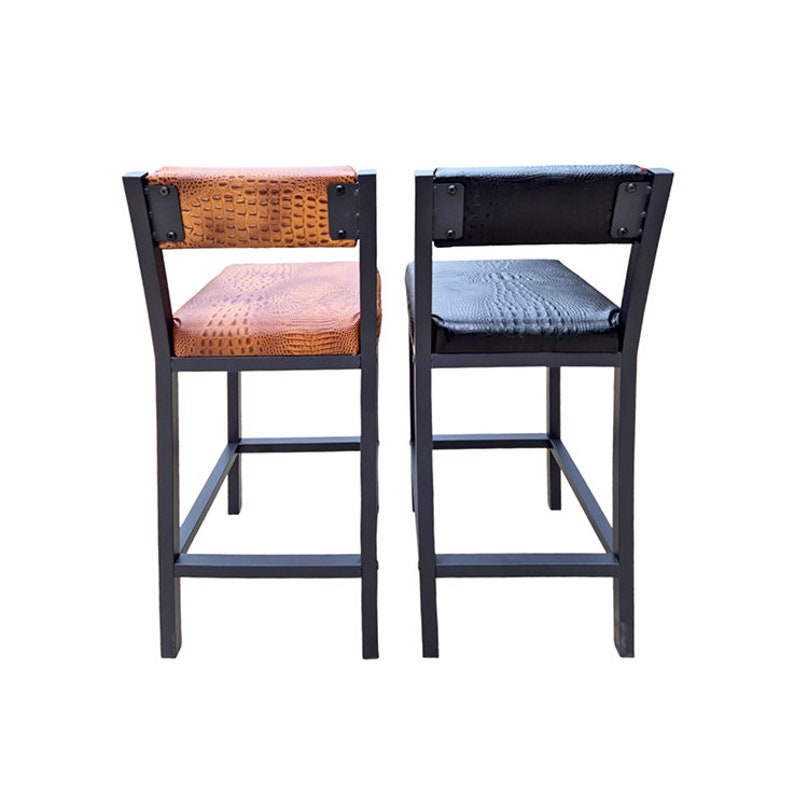May include: Two bar stools with black metal frames. One stool has a brown, textured seat and back, while the other has a black, textured seat and back. The seats and backs are attached with metal brackets.