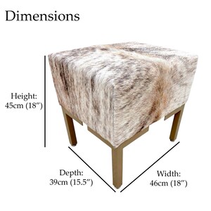 May include: A square ottoman with a cowhide pattern in shades of brown, tan, and white. The ottoman has gold-colored metal legs. Dimensions: 18" wide, 15.5" deep, and 18" high.