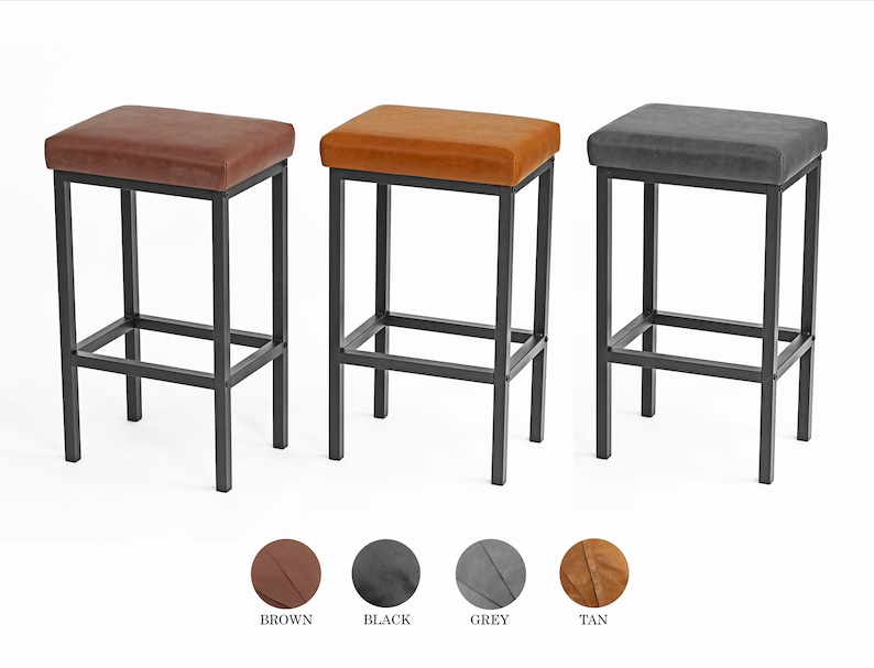 May include: Three bar stools with black metal frames and upholstered seats. The stools are available in brown, black, and gray.