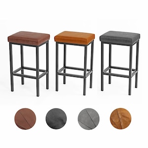May include: Three bar stools with black metal frames and upholstered seats. The seats are available in brown, black, and gray.
