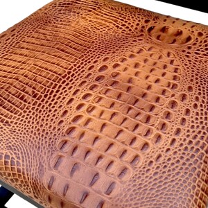 May include: A brown leather chair with a crocodile-embossed pattern on the seat. The chair has a black metal frame.