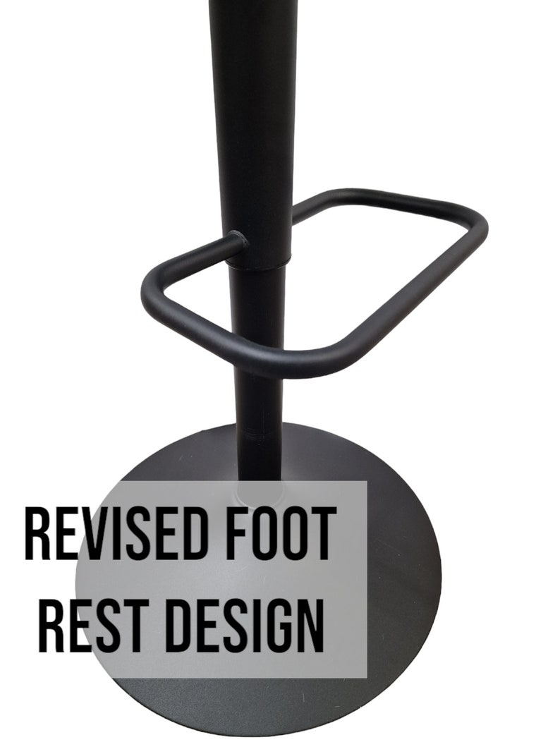 May include: Black metal bar stool with a footrest and a round base. The footrest has a revised design. The text "REVISED FOOT REST DESIGN" is printed on the base.