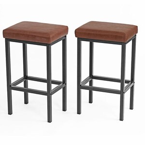 May include: Two brown leather bar stools with black metal frames. The stools have a simple design with a rectangular seat and a single crossbar for support.