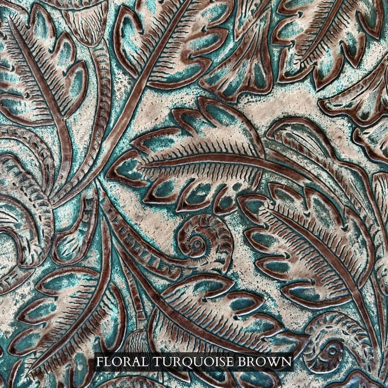 Op de afbeelding: Een close-up van een turquoise en bruin leer met een reli&euml;fpatroon van bloemen. Het leer heeft een textuur en een verweerde uitstraling.