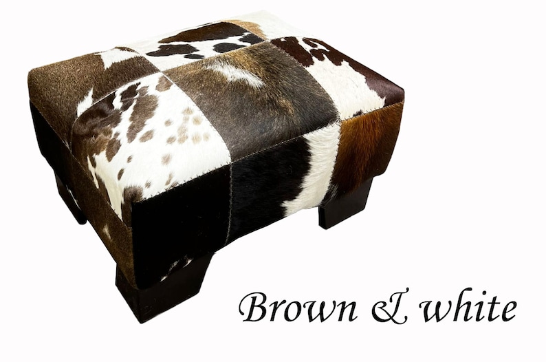 May include: A brown and white patchwork cowhide ottoman with wooden legs.