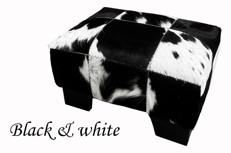 May include: Black and white cowhide ottoman with a patchwork design. The ottoman has four black legs.