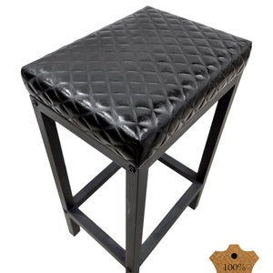 May include: Black bar stool with a diamond-stitched leather seat. The stool has a simple, sturdy design with a square base and four legs. The seat is padded and comfortable. The stool is made of high-quality materials and is built to last. 100% Genuine Leather.