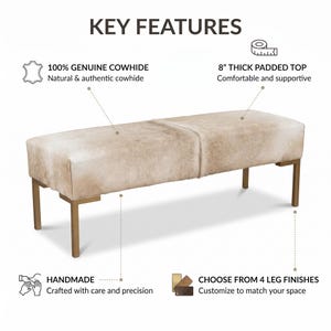 May include: A rectangular bench featuring a light beige cowhide upholstered seat and four metallic gold legs. Text labels indicate key features including 100% genuine cowhide, an 8-inch thick padded top, handmade construction, and four leg finish options.