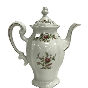 May include: White porcelain teapot with a floral rose pattern. The teapot has a curved handle, a spout, and a lid with a decorative finial. The floral design features pink roses and green leaves. The teapot has gold trim.