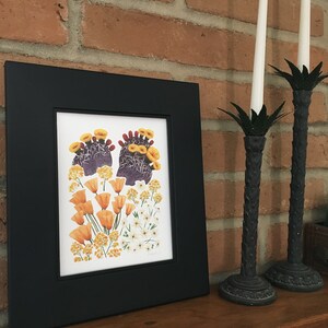 May include: A framed botanical print featuring a cluster of orange and yellow flowers, including poppies and prickly pear cactus blossoms, on a white background.