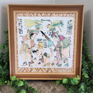 May include: A framed print depicting a detailed illustration of ancient figures in colorful attire. The artwork features multiple figures, some kneeling, with intricate headdresses and patterns. The frame is a warm brown with a decorative border.