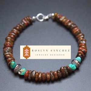May include: A brown and turquoise beaded bracelet with silver accents. The bracelet is made with small, round beads and features a clasp closure. ROSLYN SANCHEZ JEWELRY DESIGNER is printed on a white label.