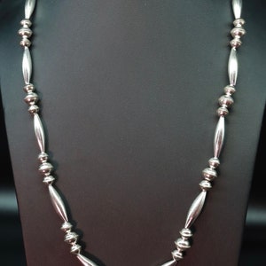 May include: A silver necklace with a repeating pattern of round and oval beads.