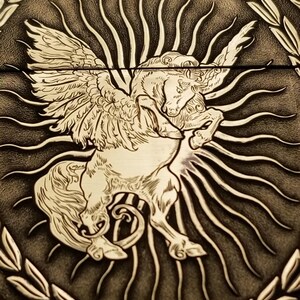 以下が含まれることがあります： 羽根のある馬、またはペガサスを詳細に描いた、エンボス加工された革のデザイン。その背後には太陽の光線が放射状に広がっています。デザインは茶色と白のグラデーションで表現されています。