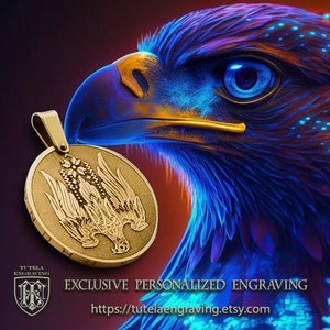 May include: A gold pendant with a detailed engraving of a stylized eagle with wings spread. The pendant is on a dark background with a blue and purple eagle head.