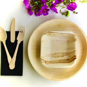 May include: A set of three disposable plates made from palm leaves. The plates are brown and have a natural, textured finish. The set includes a large plate, a smaller plate, and a small bowl. The plates are arranged on a white surface.