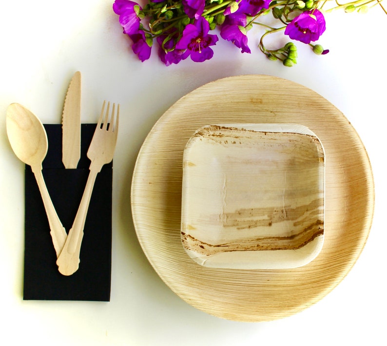 May include: A set of three disposable plates made from palm leaves. The plates are brown and have a natural, textured finish. The set includes a large plate, a smaller plate, and a small bowl. The plates are arranged on a white surface.