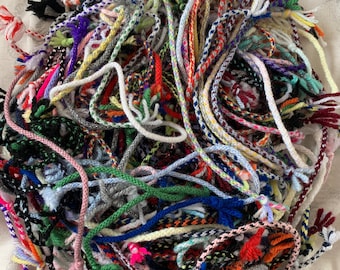 Può includere: Un grande mucchio di cordoni intrecciati colorati con vari motivi e colori, tra cui rosso, blu, verde, giallo, bianco e nero.