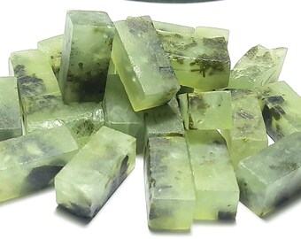 May include: A pile of translucent green soap bars with flecks of green and black throughout. The bars are rectangular and have a slightly rough texture.