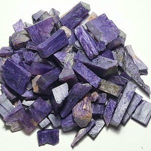 May include: A pile of purple and gray chalcedony gemstone chips. The chips are rough and have a natural, irregular shape.