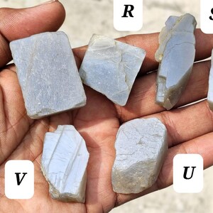 May include: Six rough, light gray, translucent mineral specimens labeled Q, R, S, T, U, and V. Each stone features irregular, angular shapes with visible natural fractures, smooth surfaces, and varying opaque to semi-translucent textures.