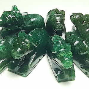 May include: A group of seven green jade carvings of mythical creatures, possibly elephants or bulls, with intricate details. The carvings are smooth and polished, with a deep green colour.