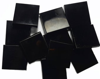 May include: A collection of eleven square tiles with a smooth, glossy black finish. Each tile features a flat surface and sharp, defined edges, arranged in an overlapping, scattered formation against a plain white background.