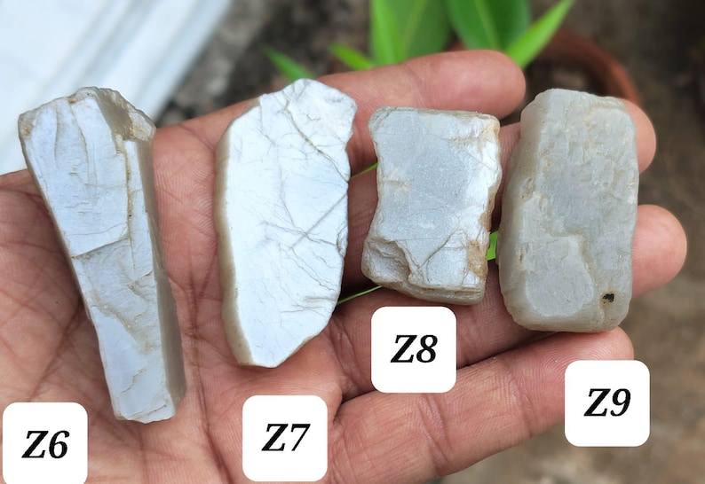 May include: Four rough, pale greyish-blue stones with irregular, fractured surfaces and visible internal veining. Each stone is labeled with a white square containing black text: Z6, Z7, Z8, and Z9, identifying four distinct mineral specimens.