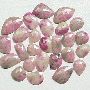 May include: A collection of 20 pink and white gemstone cabochons, each with a unique, faceted shape. The stones have a translucent appearance and a variety of pink hues.