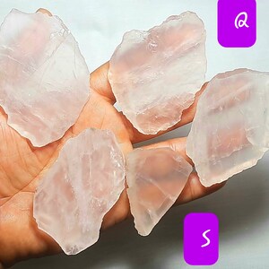 May include: Six pieces of clear, pale pink, translucent, natural rose quartz crystals. The crystals are irregularly shaped and have a smooth, polished surface.