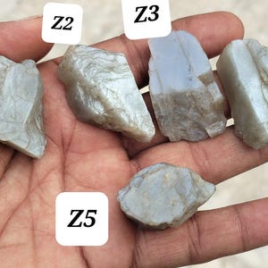 May include: Five rough, translucent, light blue-grey stones labeled Z1, Z2, Z3, Z4, and Z5. Each stone has an irregular, jagged shape with visible crystalline textures and smooth, reflective surfaces. The stones vary in size and angularity.
